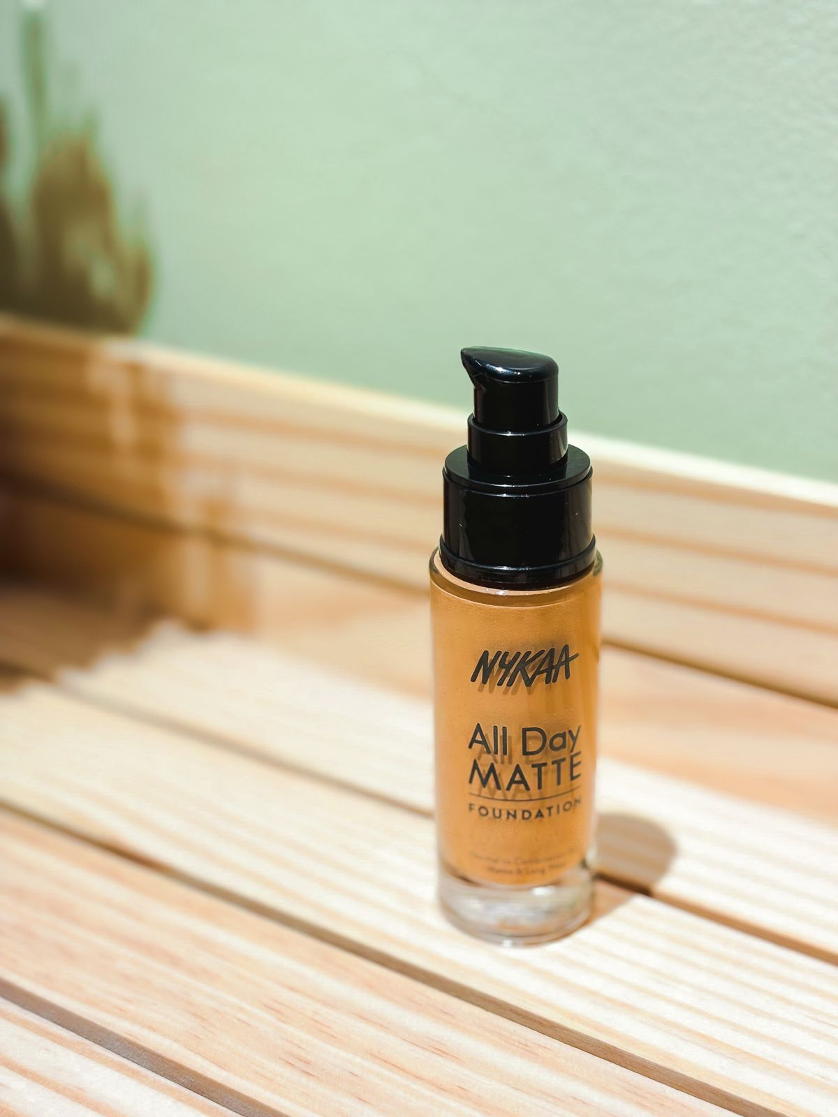A liquid foundation bottle sitting on a wooden surface with soft natural lighting
