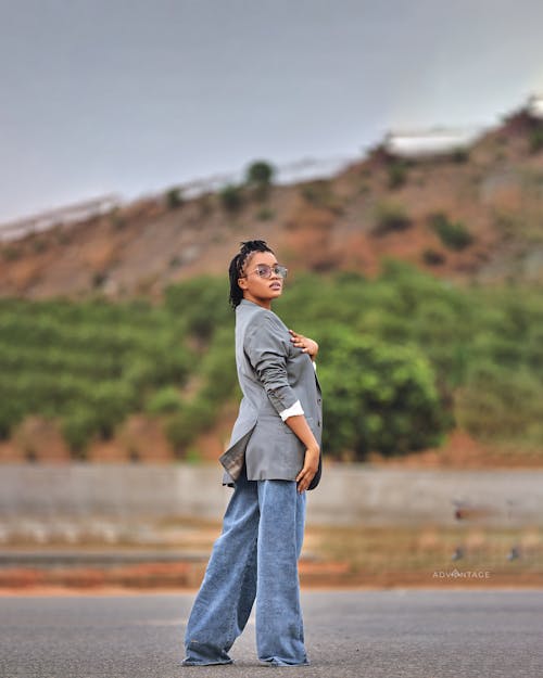 A woman in jeans and a blazer standing on a road