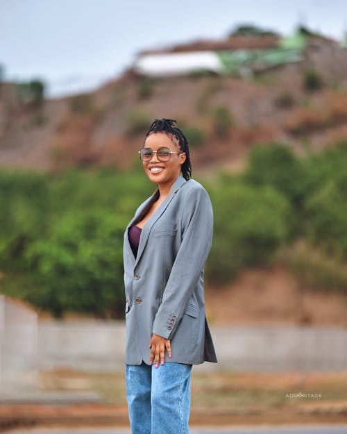 A woman in a blazer and jeans standing on a road