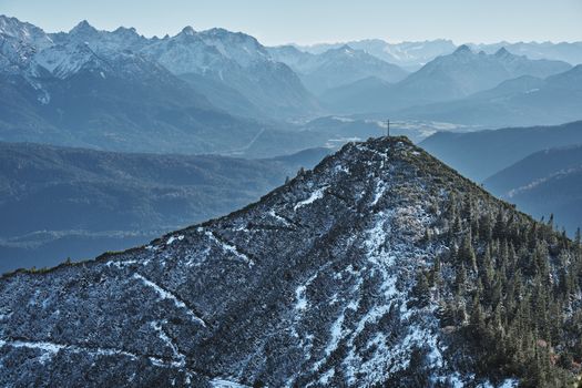 A stunning view of a snow-covered mountain peak surrounded by a vast scenic valley in winter.