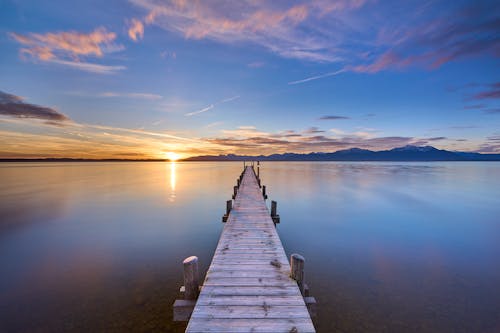 A wooden pier in the middle of a lake at sunset