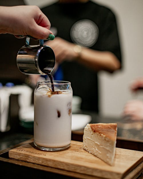 Free A person pouring milk into a glass of coffee Stock Photo
