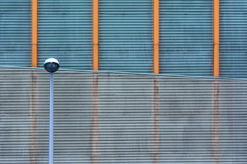 A street light and a wall with orange and blue stripes