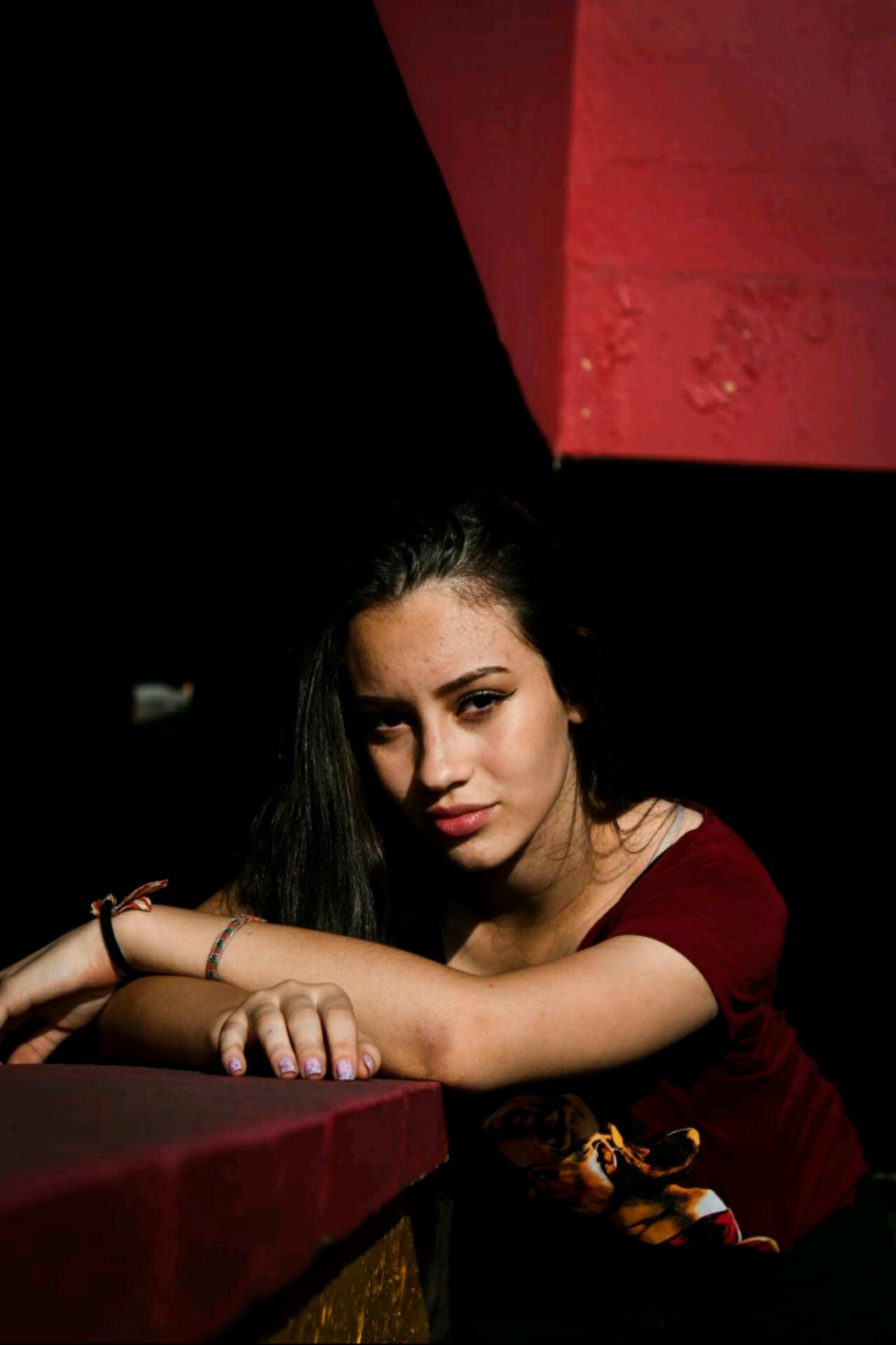 柔和的灯光下，一位年轻女子倚着栏杆，她的亲密肖像捕捉到一种富有表现力的情绪