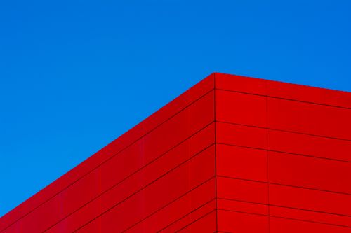 Free Dynamic shot of vibrant red building against a clear blue sky in modern Capelle aan den IJssel. Stock Photo