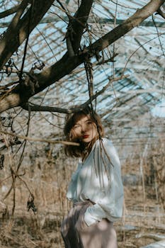 一位时尚女性在树枝间摆姿，营造出自然的艺术构图