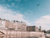 人们沿着海滨漫步，欣赏蓝天下沿河的历史建筑风景