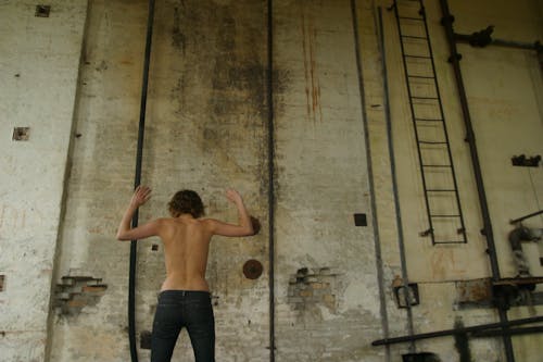 Topless Man Beside Gray Wall