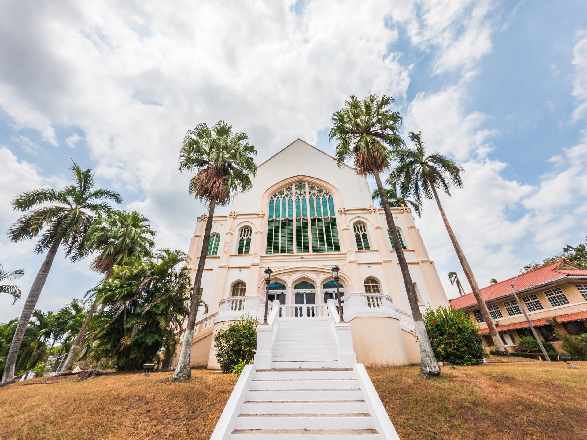 Front view of the historic Balboa Union Church in Panama City, showcasing colonial architecture with palm trees.