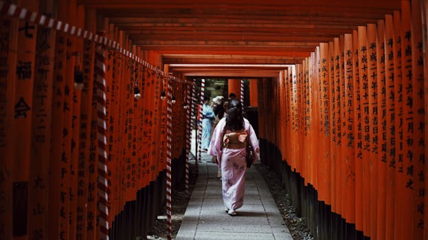 A woman in a kimono walks through the famous Torii gates of Fushimi Inari Shrine in Kyoto, Japan.