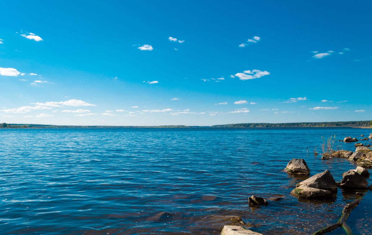 Wide blue lake under a clear sky with a rocky shoreline