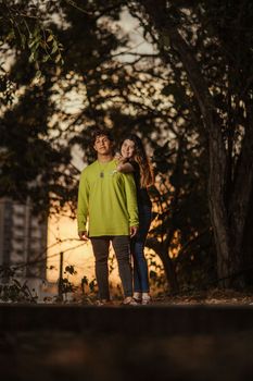 一对年轻夫妇在日落时分于户外相拥，与自然融为一体，尽显浪漫