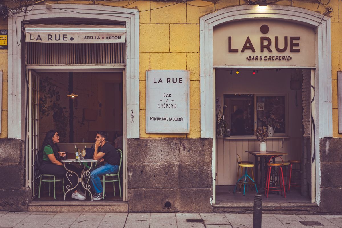 Doua persoane la o terasa de cafenea, pe strada