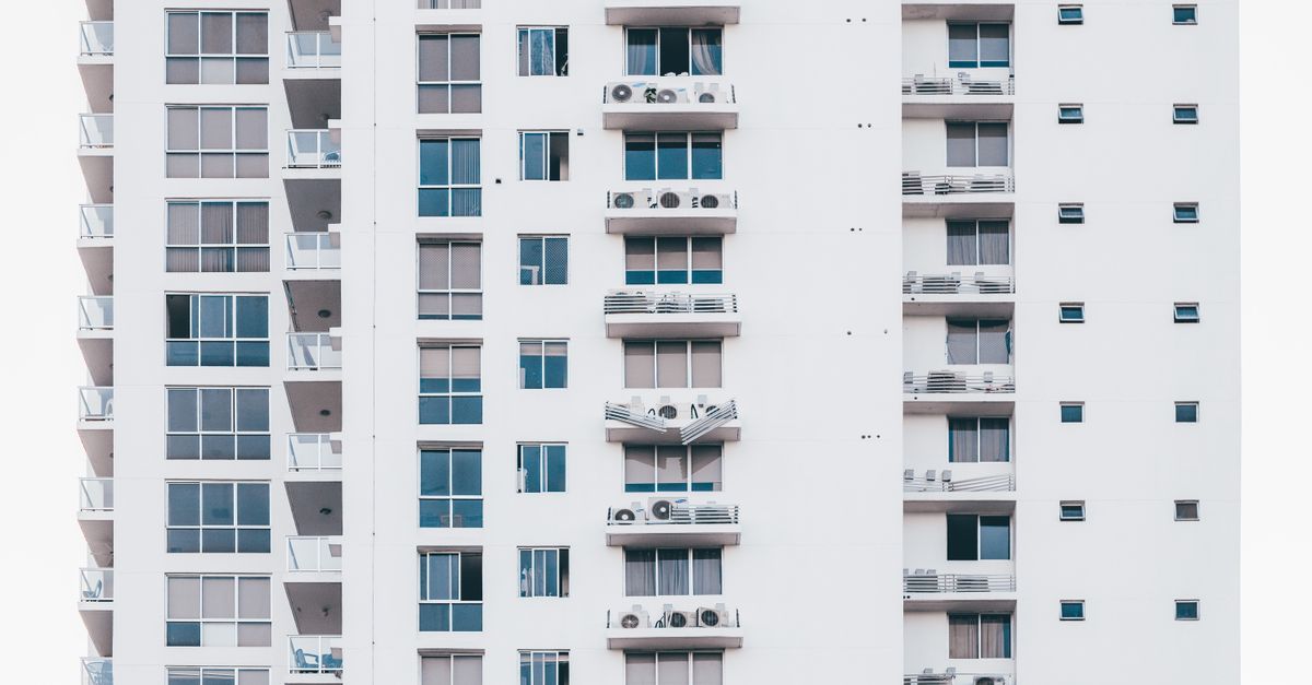 A sleek, modern high-rise building with a glass facade and multiple balconies, showcasing urban architecture.