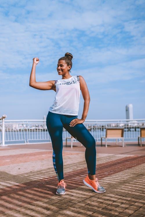 Woman in White Tank Top Standing on Concrete Surface