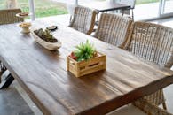 舒适的室内用餐区设有乡村风格的木桌，装饰着植物和柳条椅子