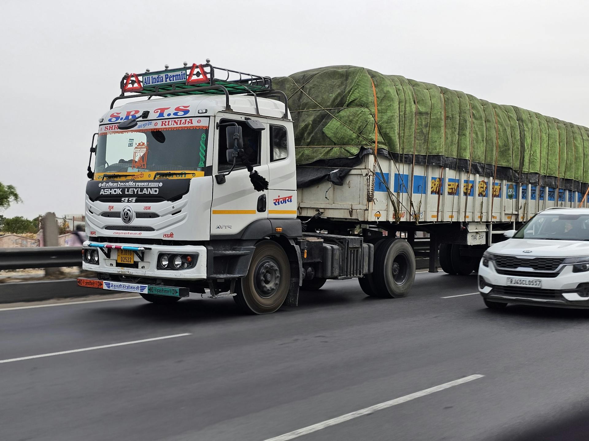 Ashok Leyland semi-truck transporting goods on a busy Indian highway, showcasing modern logistics.