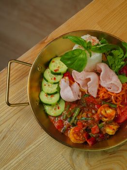 Colorful Indonesian Gado-Gado salad with fresh vegetables and shrimp in a brass bowl.