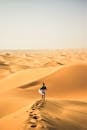 一位孤独的旅行者走过阿尔及利亚撒哈拉沙漠的广阔沙丘