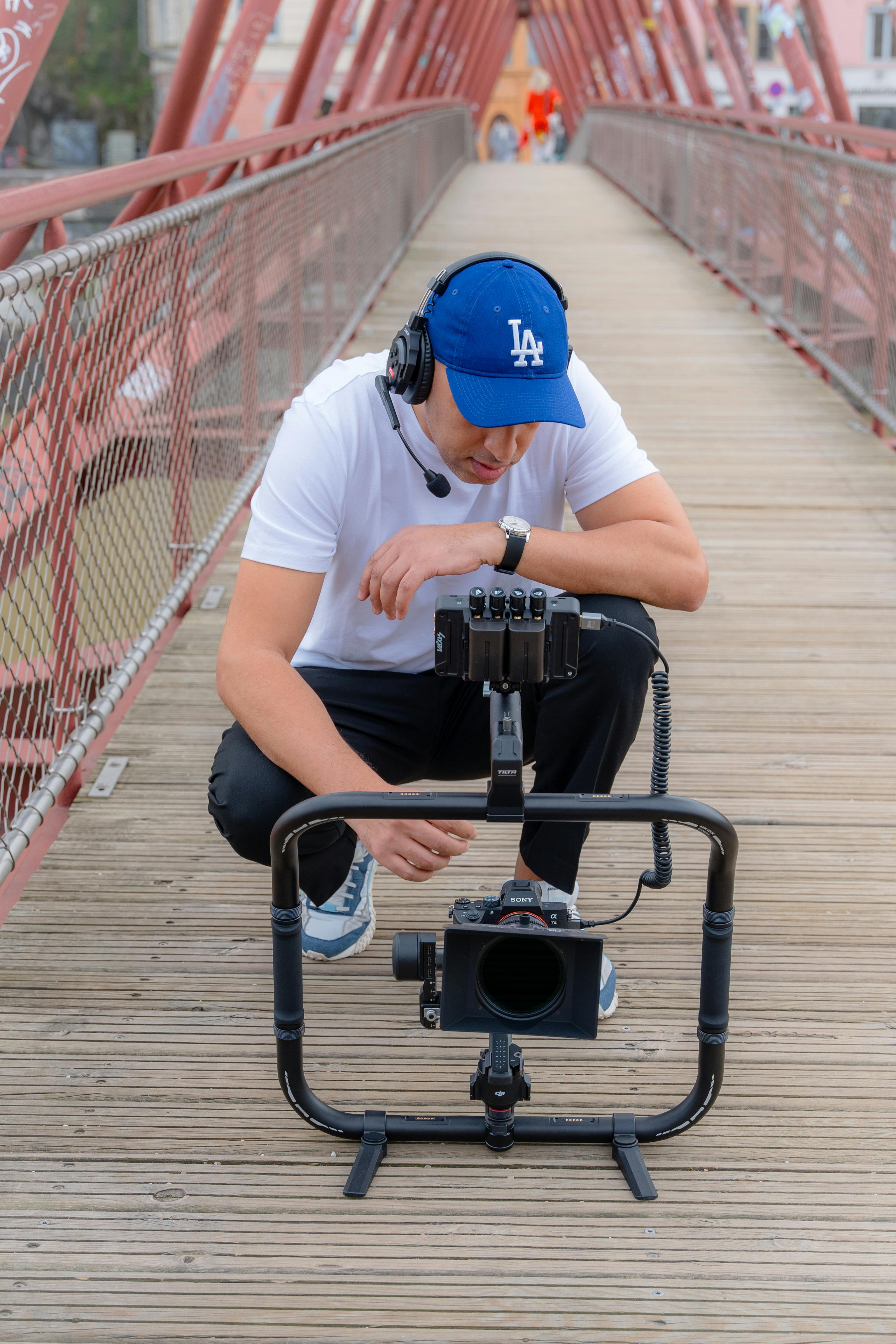 man with a photographic equipment squatting on a footbridge