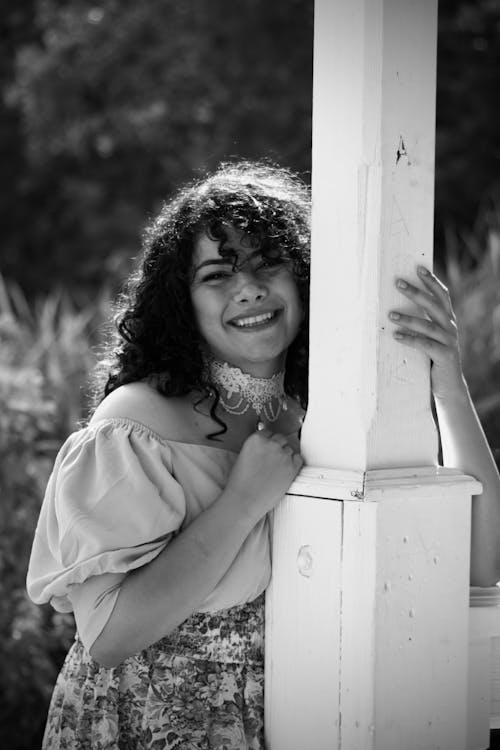 Woman with Curly Hair Holding Column and Smiling