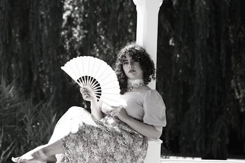 A woman sitting on a bench holding a fan