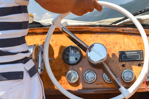 A man is steering a boat with a steering wheel