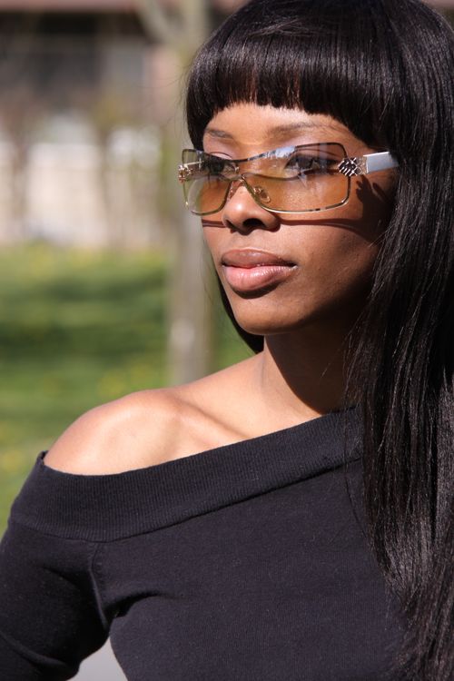 Free Elegant portrait of a black woman with sunglasses, showcasing modern fashion outdoors. Stock Photo