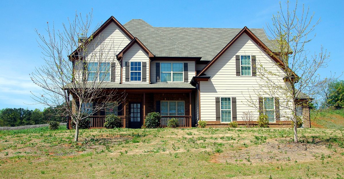 Beautiful two-story suburban home with a spacious lawn under clear blue skies.