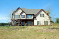 这栋美丽的两层郊区住宅，在晴朗的蓝天下拥有一片宽敞的草坪