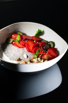 A nutritious bowl featuring chia pudding topped with fresh strawberries, nuts, and mint leaves.