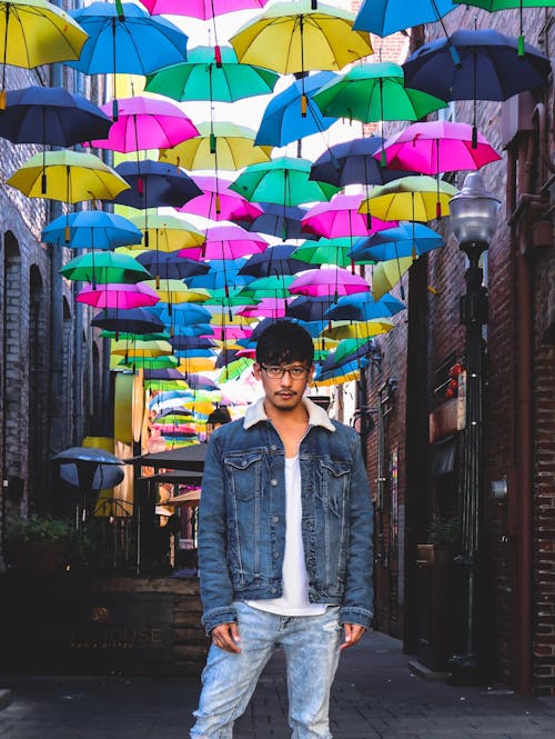 Man Standing Under Colourful Umbrellas