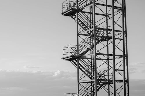 Black and white contemporary tall industrial viewing platform with staircase and observation panels against gray cloudy sky