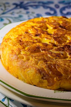 Close-up of a freshly cooked Spanish tortilla on a decorative plate, showcasing its rich texture.