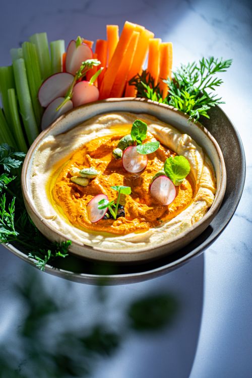 Free Creamy hummus served with fresh carrots, celery, and radishes, perfect for a healthy snack. Stock Photo