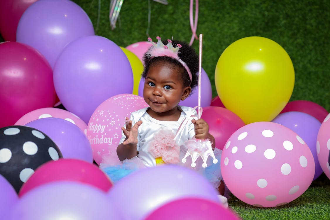 Kleinkind Mädchen, Das Auf Dem Boden Sitzt, Umgeben Von Luftballons