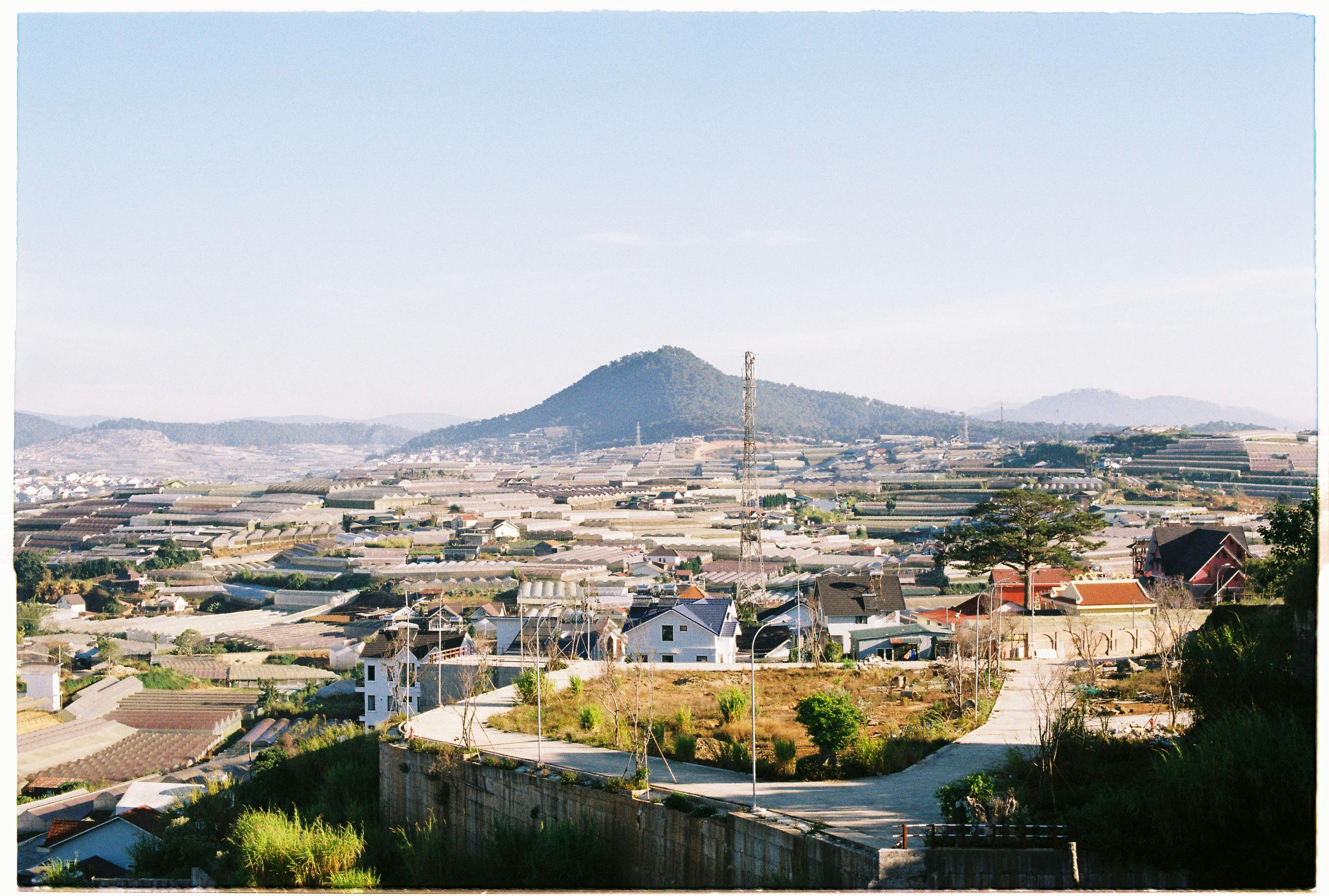 Expansive rural landscape with fields and hills under a clear sky, seen from a hilltop.