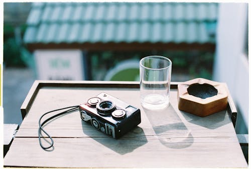 Free A camera and a glass on a table Stock Photo