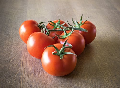 Six Orange Tomatoes Forming Triangle on Brown Surface