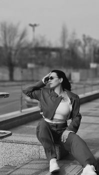 Black and white urban fashion photo of a woman posing stylishly outdoors.