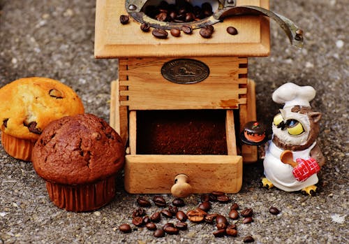 棕色木制咖啡豆研磨机和两个松饼