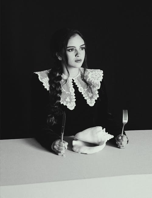 Woman Sitting with Fork and Knife in Black and White
