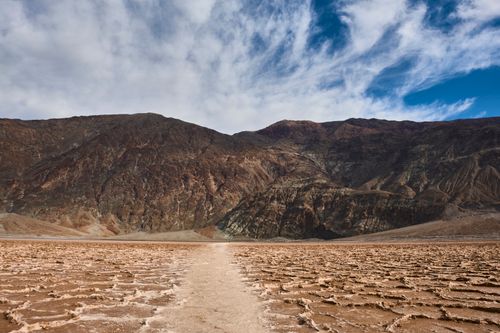 Free Stunning view of Death Valley's rugged mountains and intricate desert patterns under a vibrant sky. Stock Photo