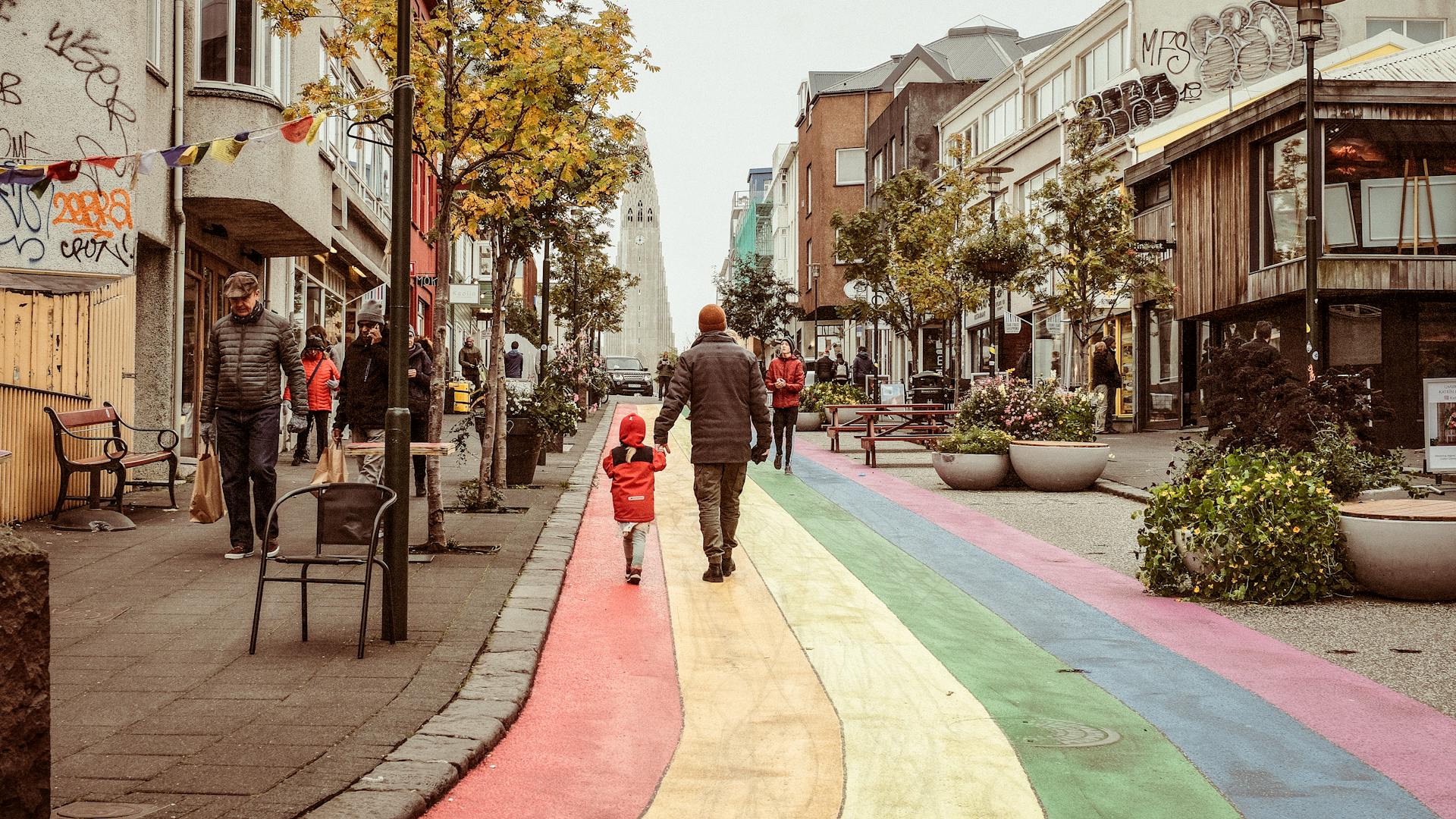 Vibrant street scene in Reykjavik with a rainbow path leading to Hallgrimskirkja church.