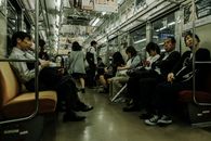 Passengers seated and standing in a busy subway train, showcasing daily public transportation.