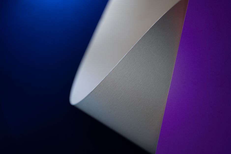 Artistic composition of geometric paper shapes in vibrant colors with a dark background.
