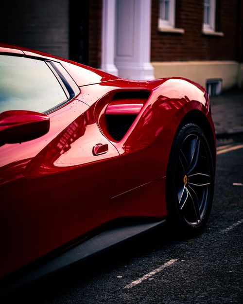 Free Close-up of a shiny red sports car parked on an urban street. Stock Photo