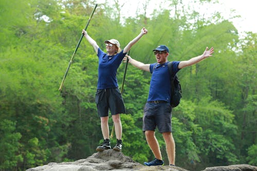 Happy Woman and Man Standing on Rock in Forest