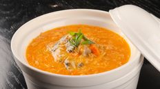 A savory pumpkin soup garnished with herbs, perfect for a cozy meal.