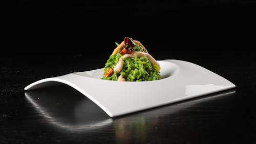 A white plate with a green salad on it